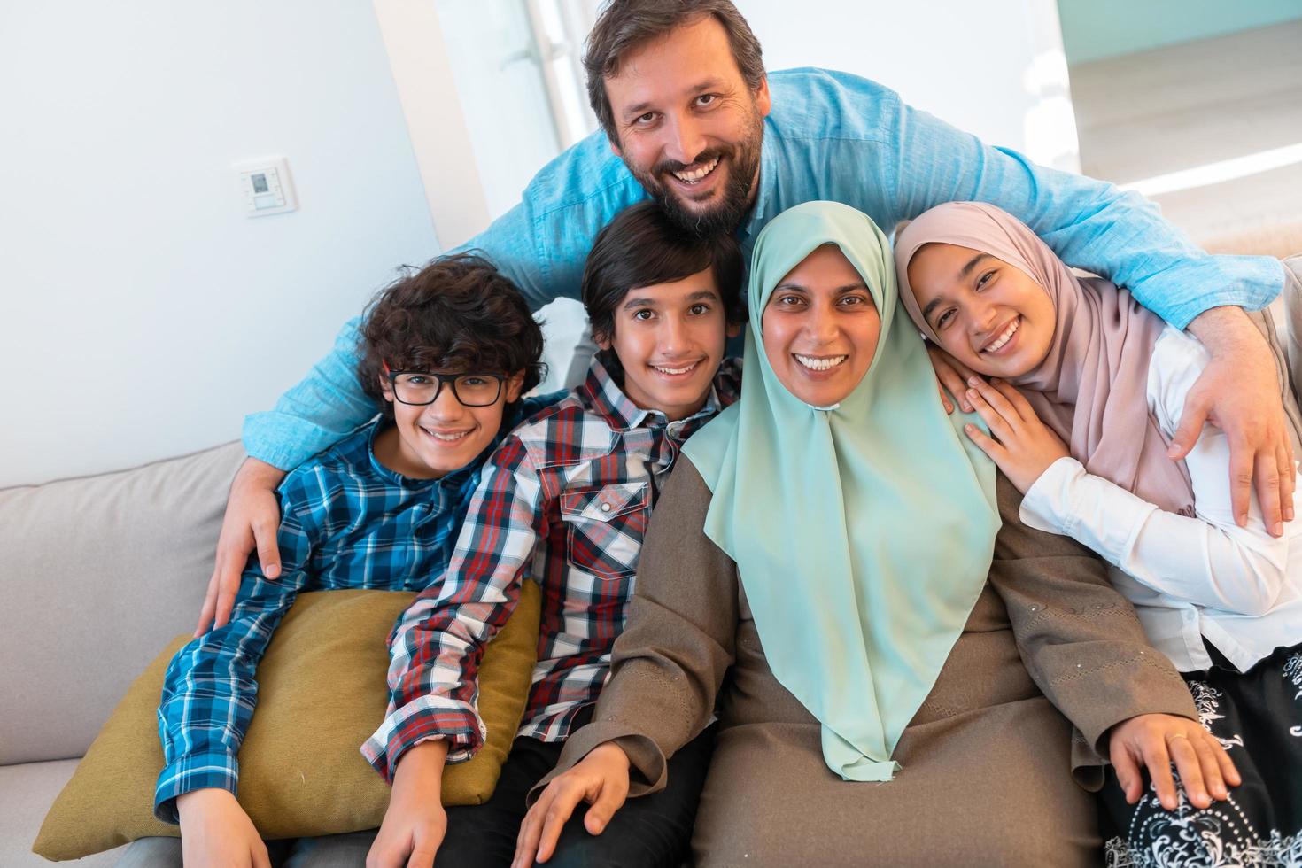 Portrait photo of an arab muslim family sitting on a couch in the living room of a large modern house. Selective focus