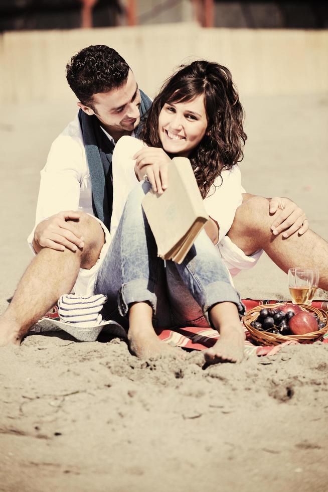 pareja joven disfrutando de un picnic en la playa foto