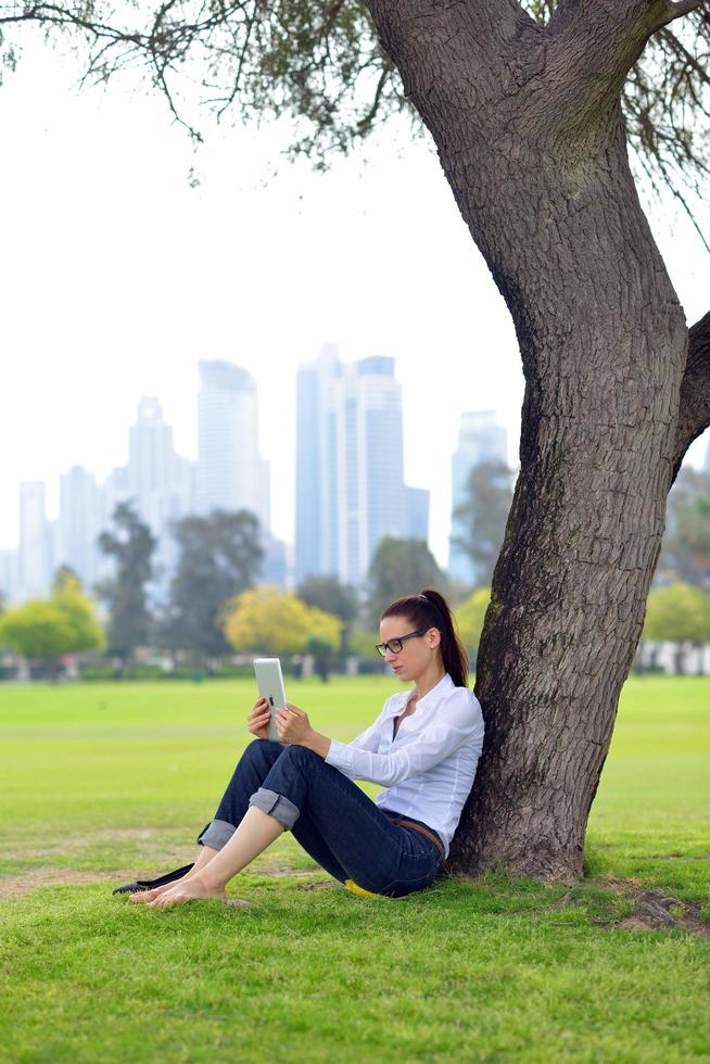 Beautiful young woman with  tablet in park photo