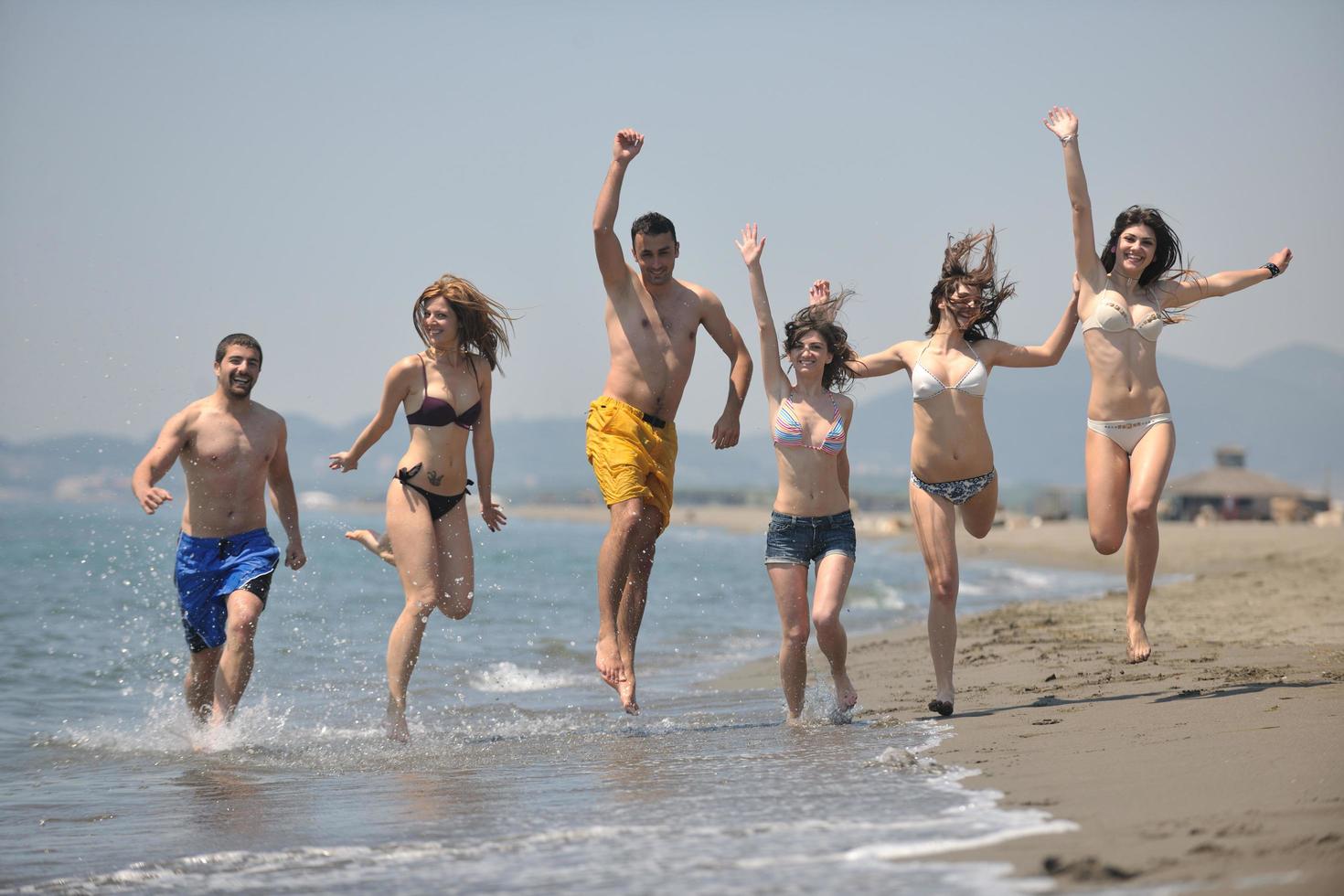 grupo de gente feliz divertirse y correr en la playa foto