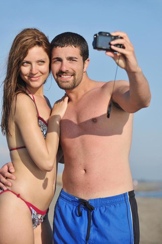 feliz pareja joven enamorada tomando fotos en la playa