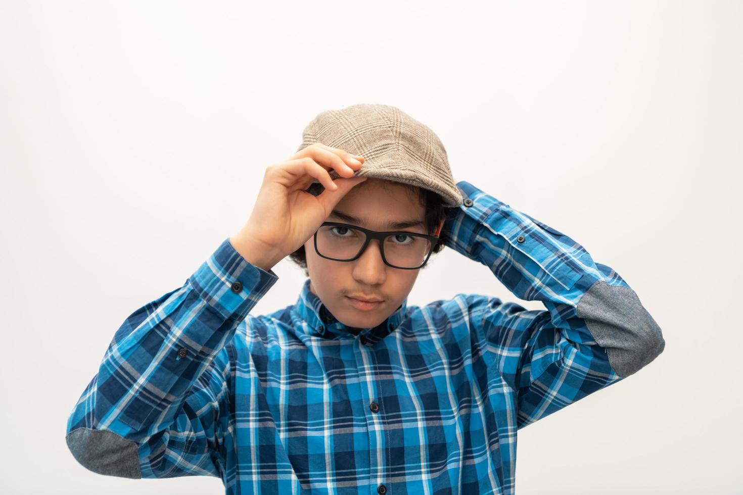 portrait of smart looking arab teenager with glasses wearing a hat in casual school look isolated on white copy space photo