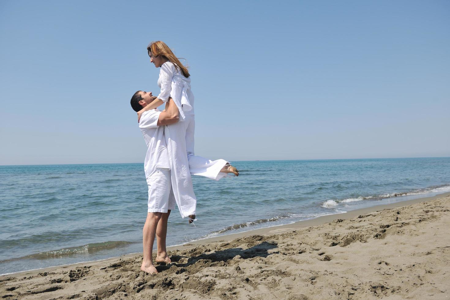 feliz pareja joven divertirse en la playa foto