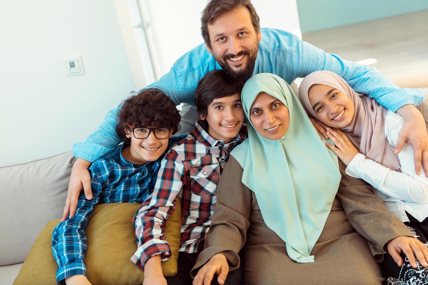 Portrait photo of an arab muslim family sitting on a couch in the living room of a large modern house. Selective focus