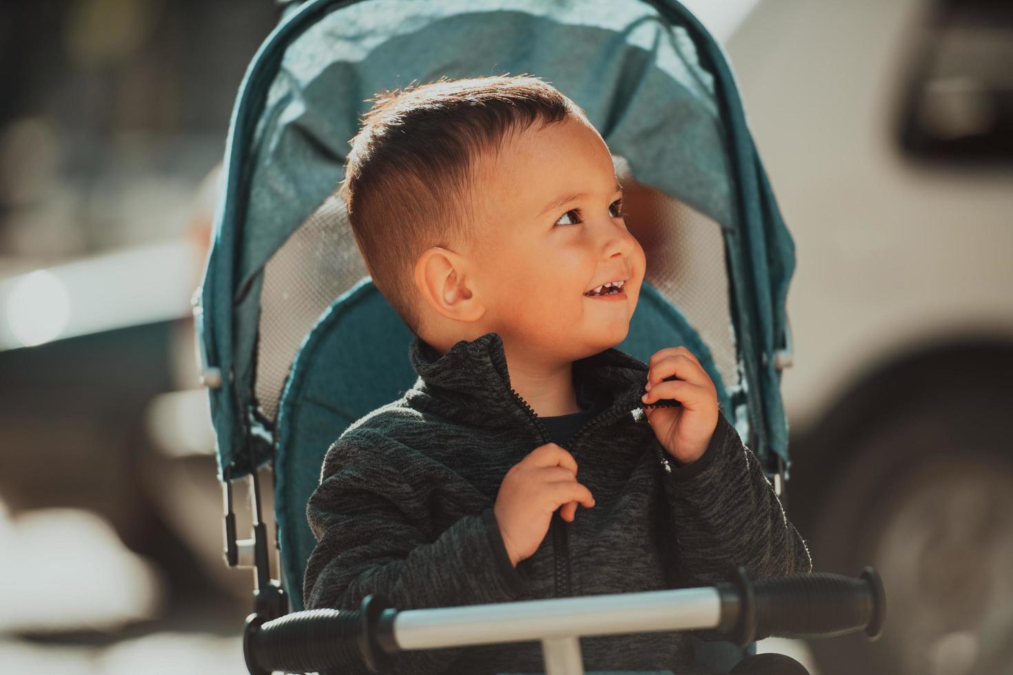 Sweet baby boy in a stroller bicycle outdoors. Little child in a pram. Infant kid in a pushchair. Spring walks with kids. photo