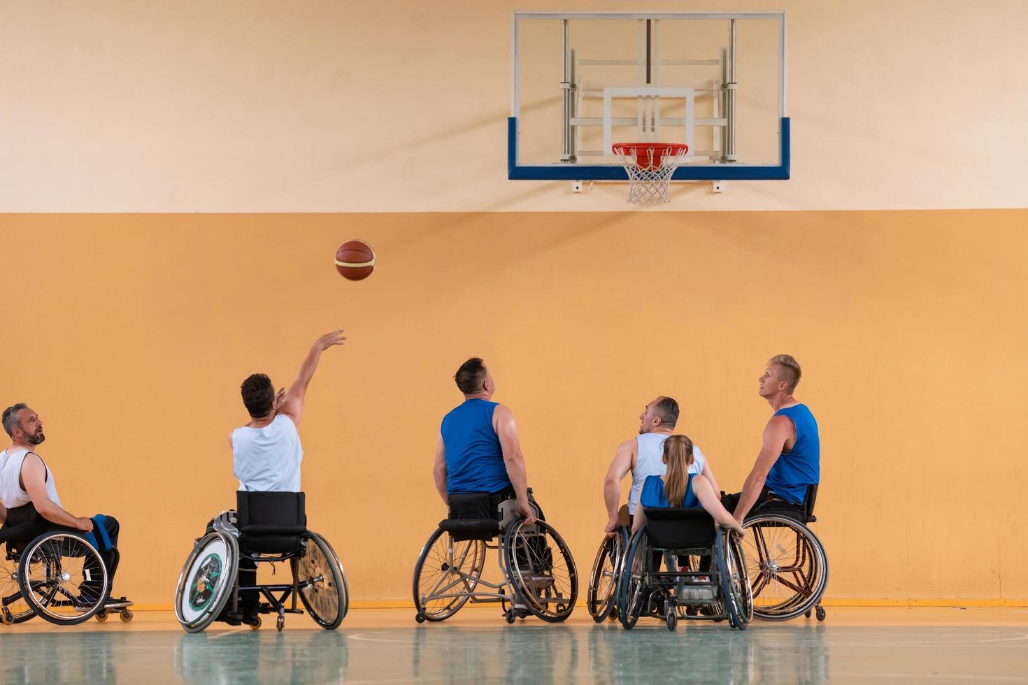 Disabled War veterans mixed race opposing basketball teams in wheelchairs photographed in action while playing an important match in a modern hall. photo