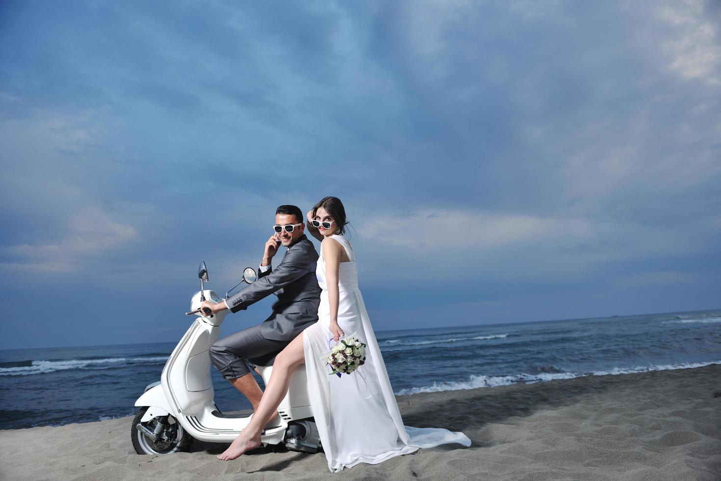 just married couple on the beach ride white scooter photo