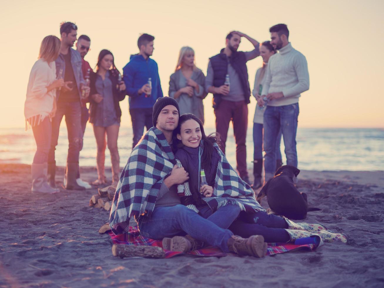 Couple enjoying with friends at sunset on the beach photo