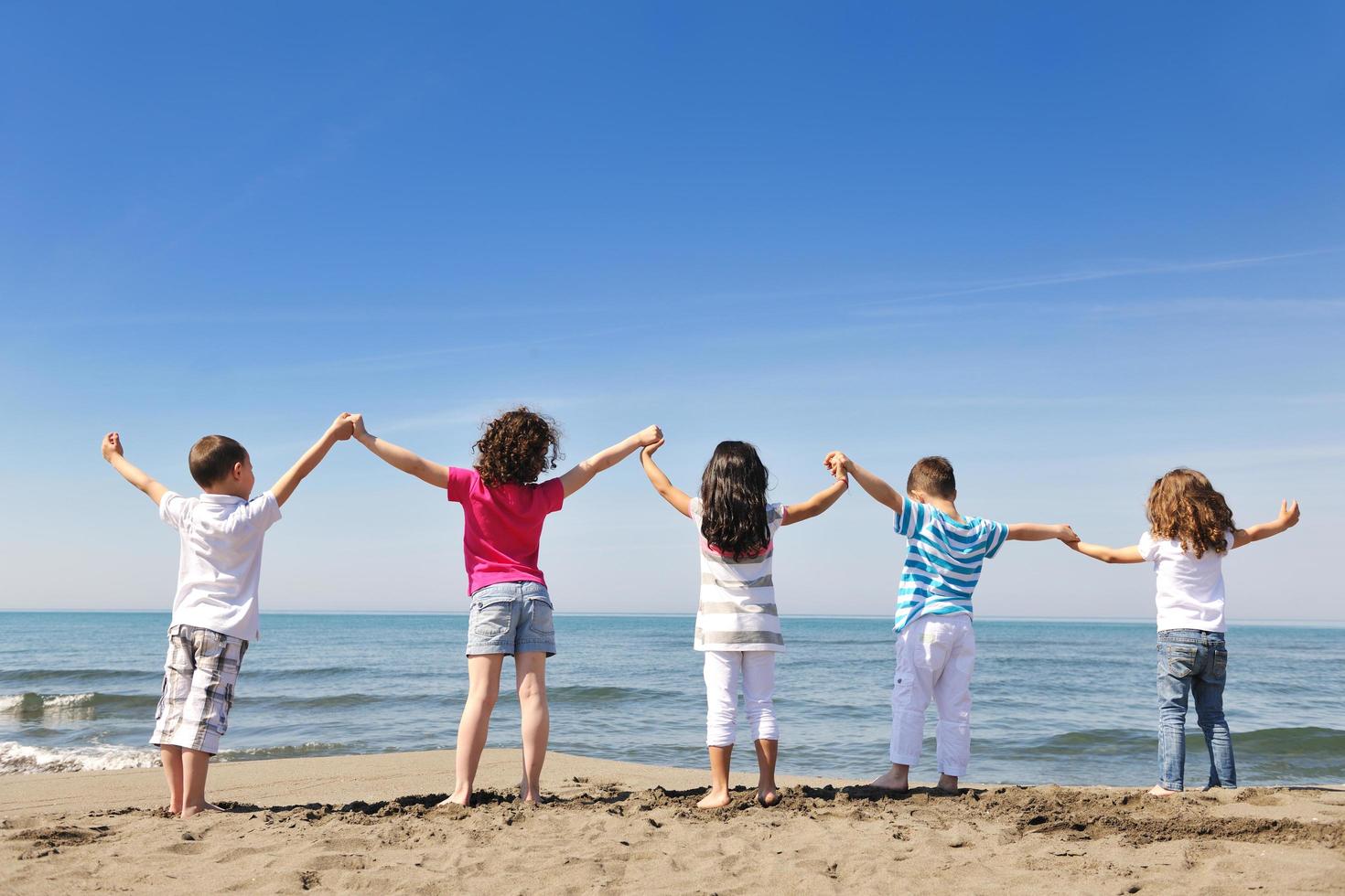 Grupo de niños felices jugando en la playa foto