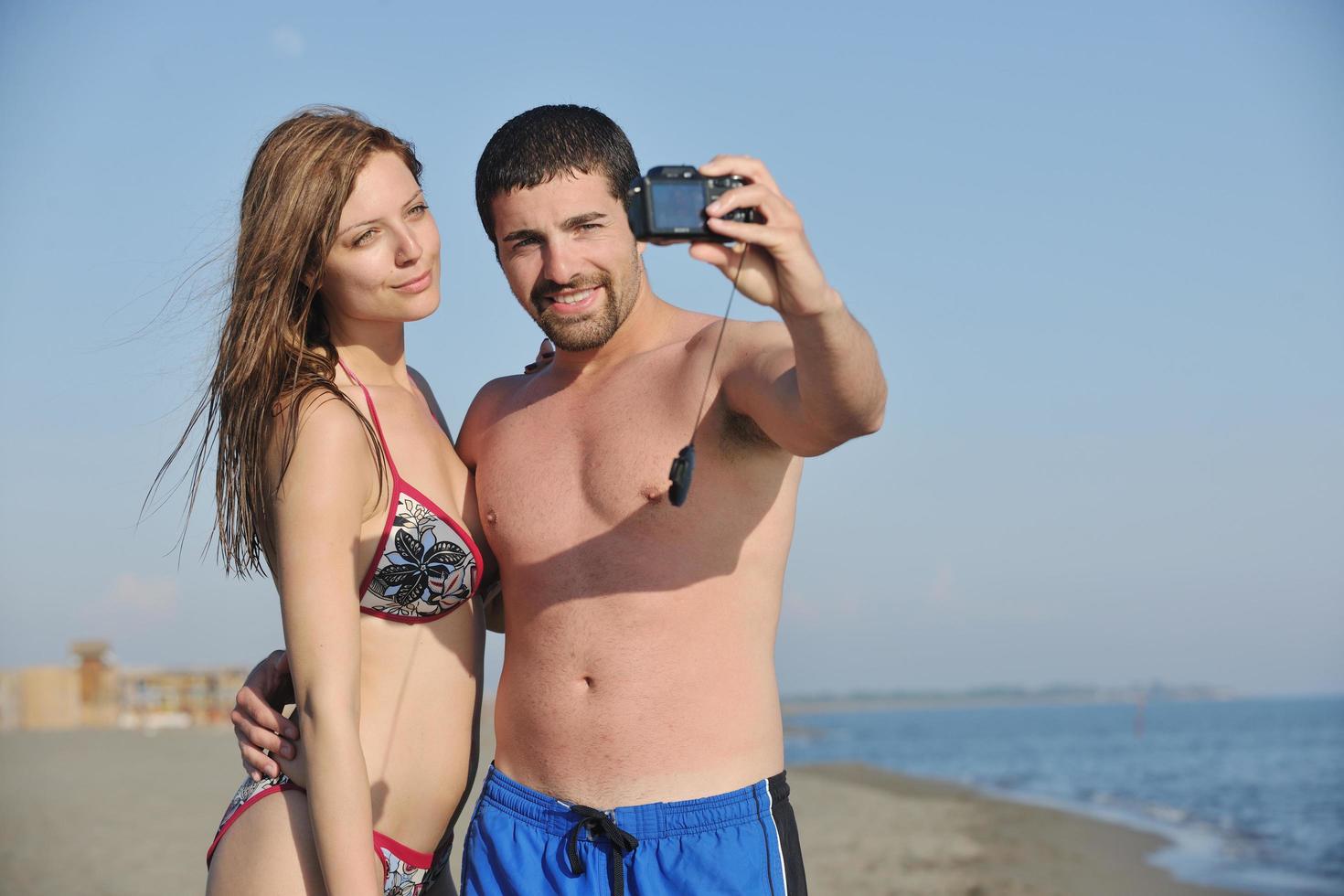 feliz pareja joven enamorada tomando fotos en la playa