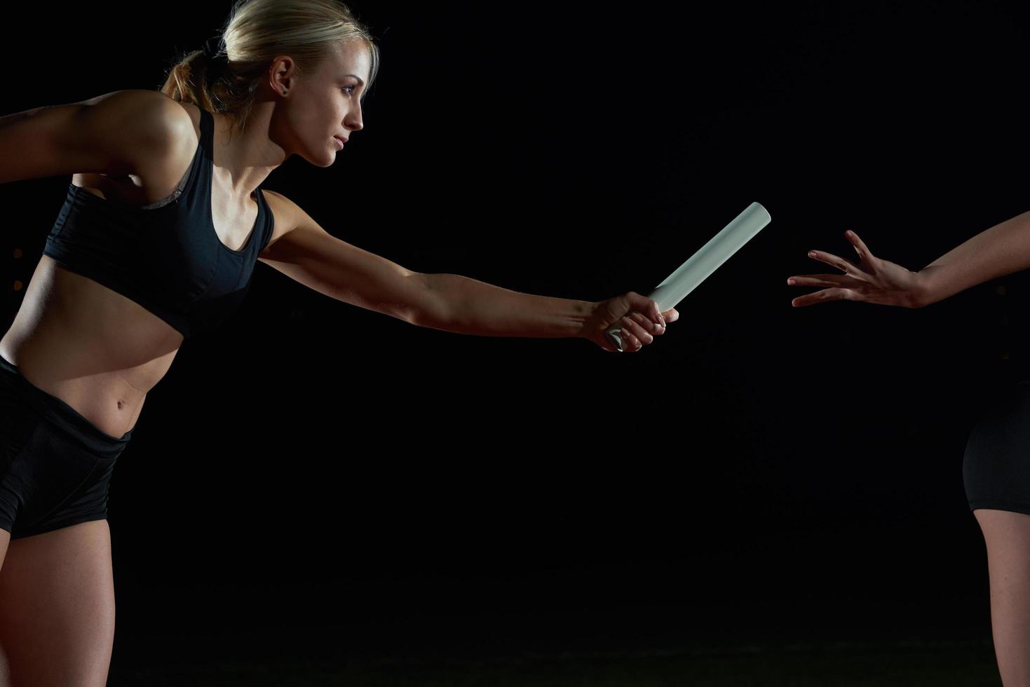 athletic runners passing baton in relay race photo