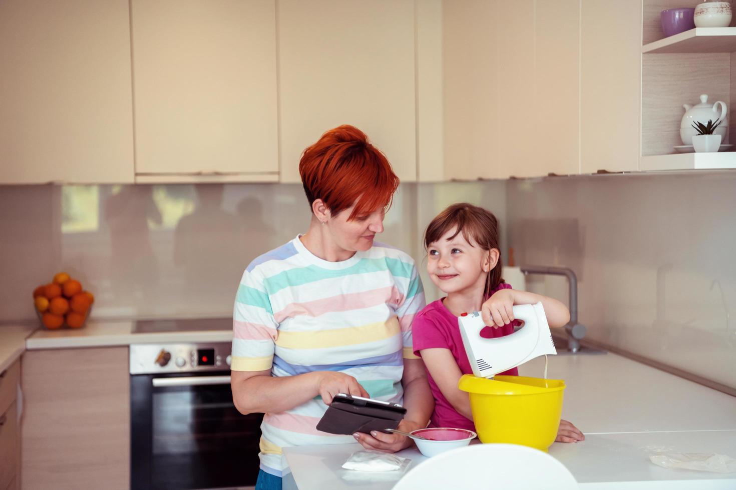 little girl and mom making tastz cake in kithen family having fun at home photo