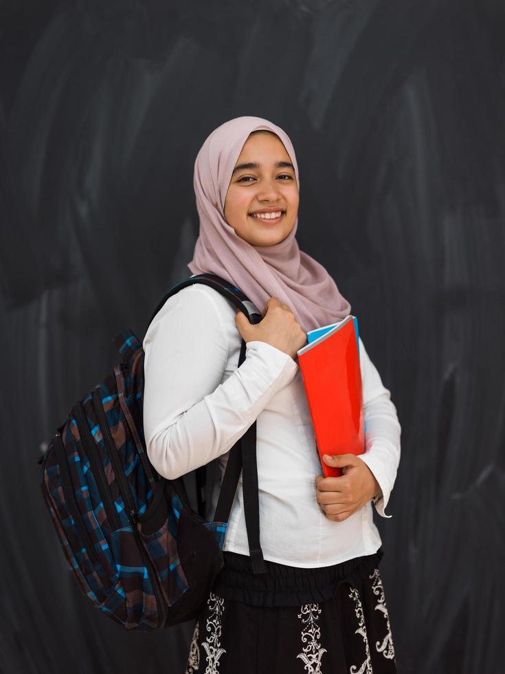 retrato de una feliz estudiante universitaria de oriente medio contra una pizarra negra en el aula foto