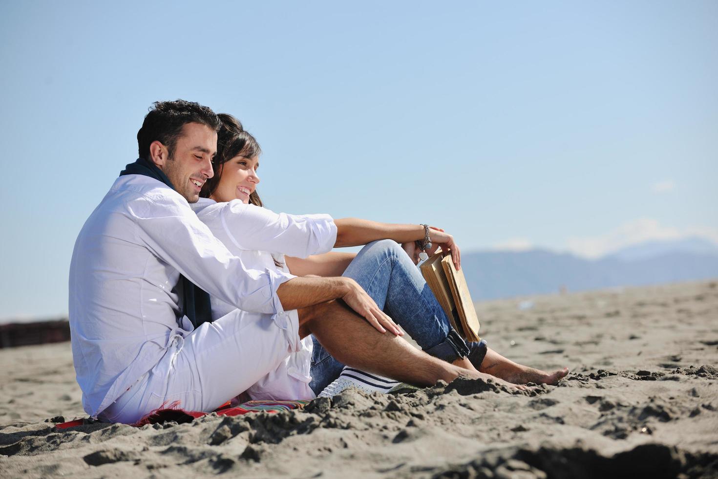 pareja joven disfrutando de un picnic en la playa foto