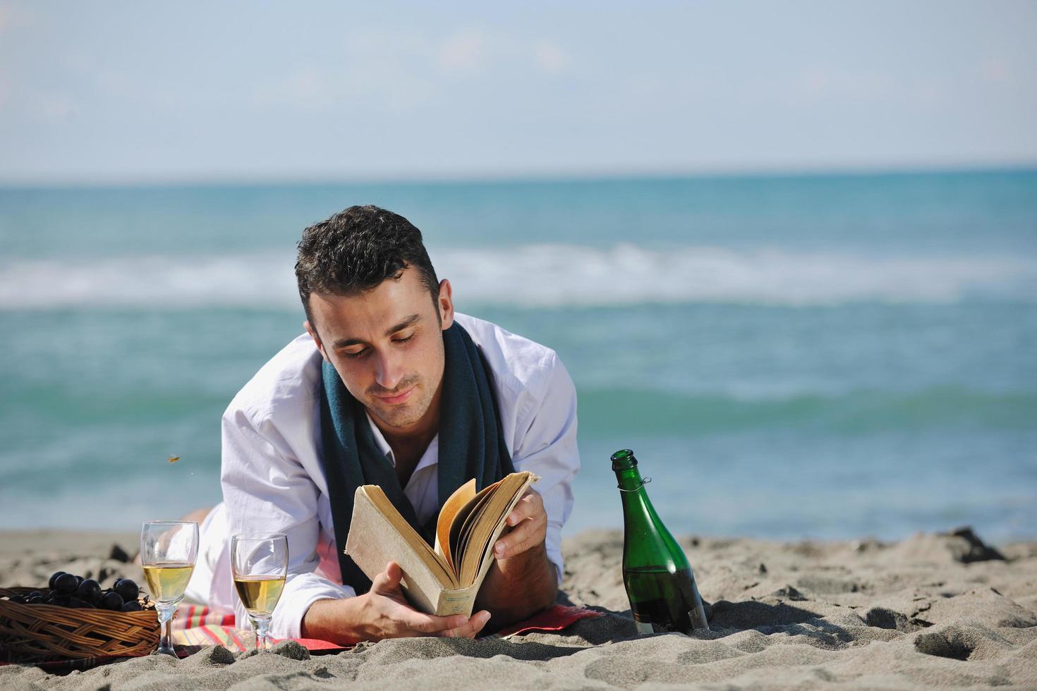 man reading book at beach photo