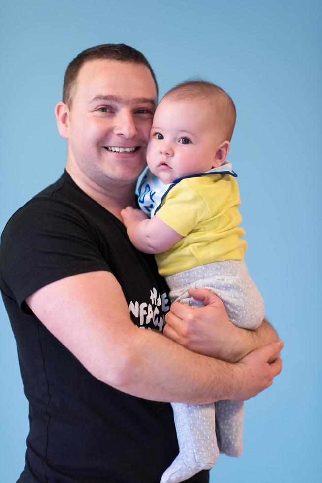 portrait of happy young father holding baby isolated on blue photo