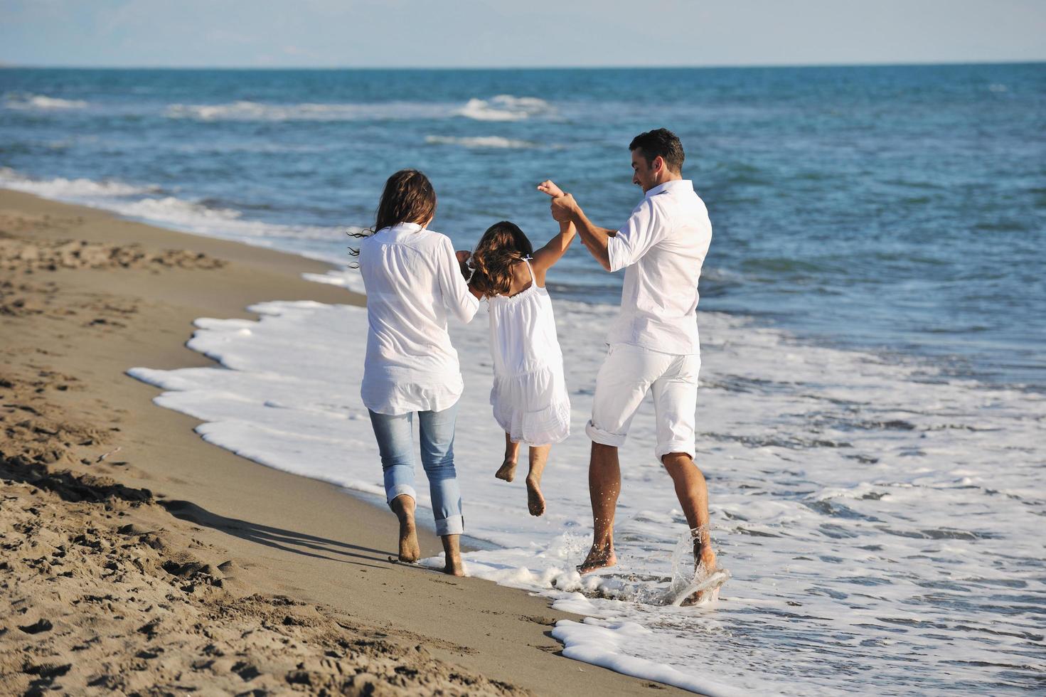 familia joven feliz divertirse en la playa foto