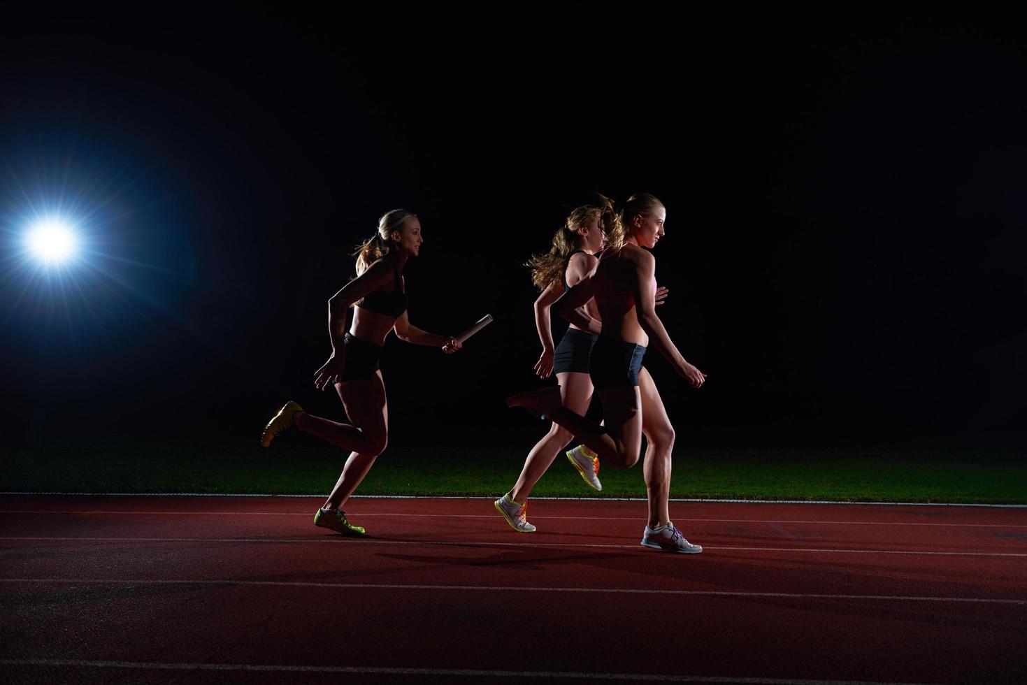 athletic runners passing baton in relay race photo