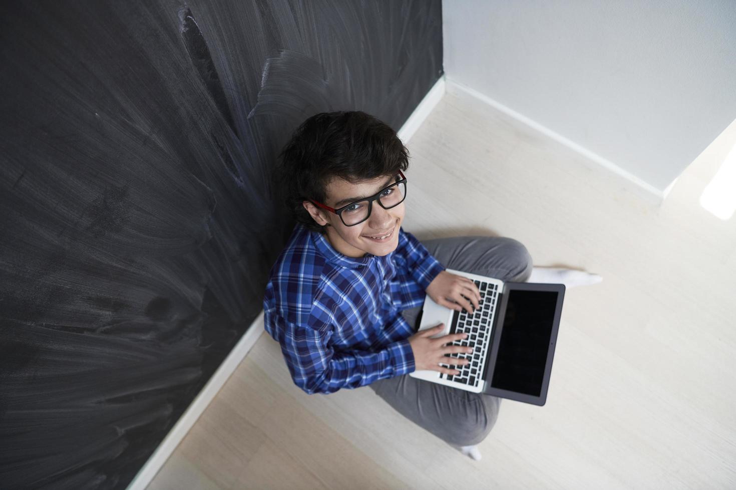 Arab teenager using laptop to work on homework  at home photo