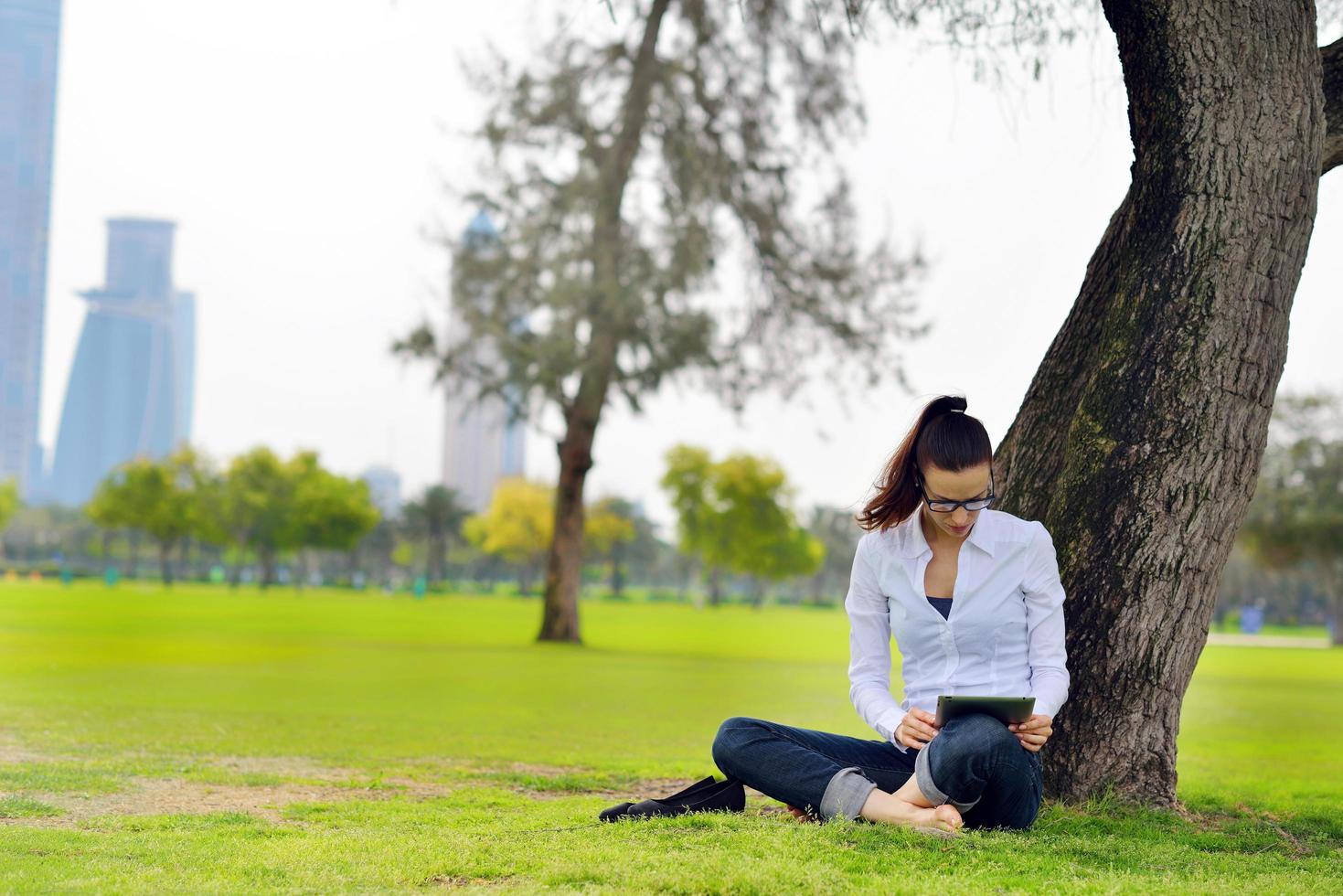 Beautiful young woman with  tablet in park photo