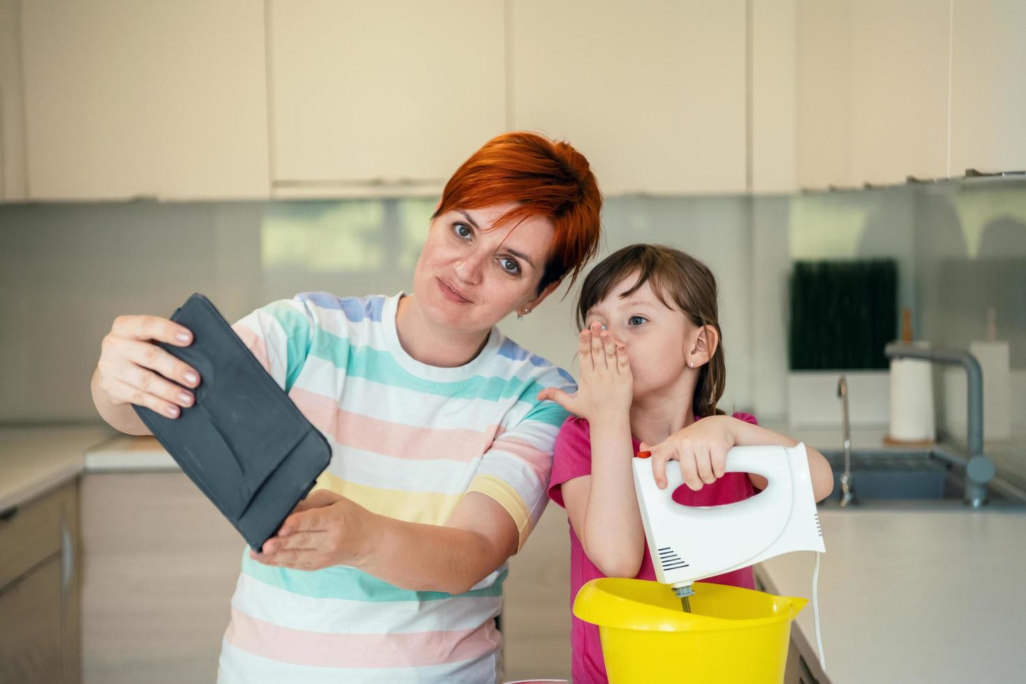 little girl and mom making tastz cake in kithen family having fun at home photo