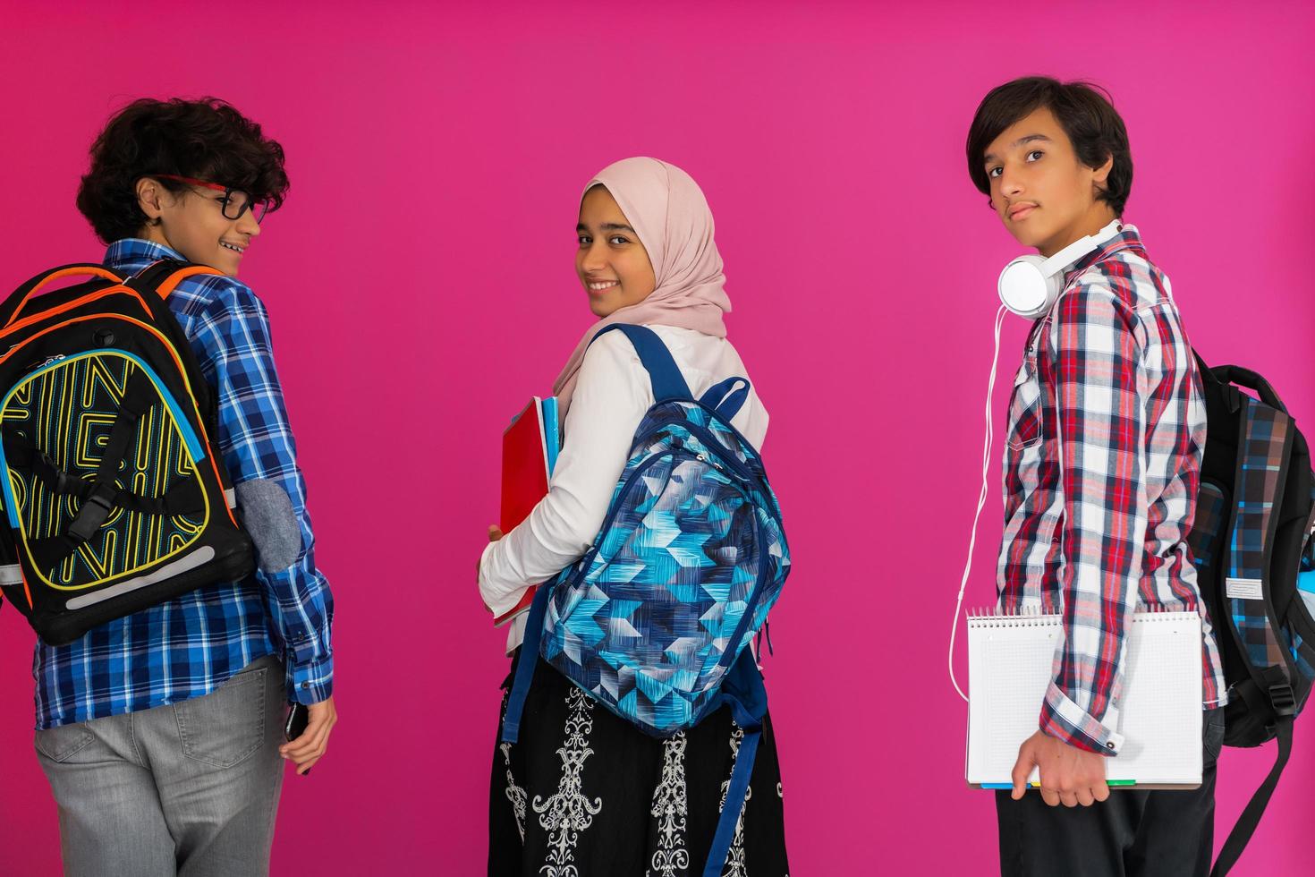A group of Arab teenagers, a student team walking forward into the future and back to school the concept of a pink background. The concept of successful education for young people. Selective focus photo