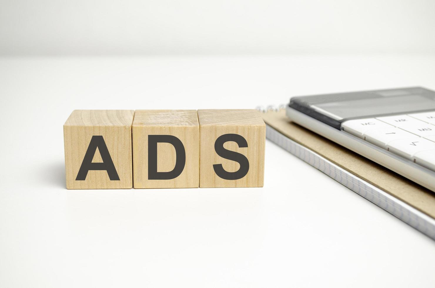 word ads on wooden blocks and calculator on white background photo