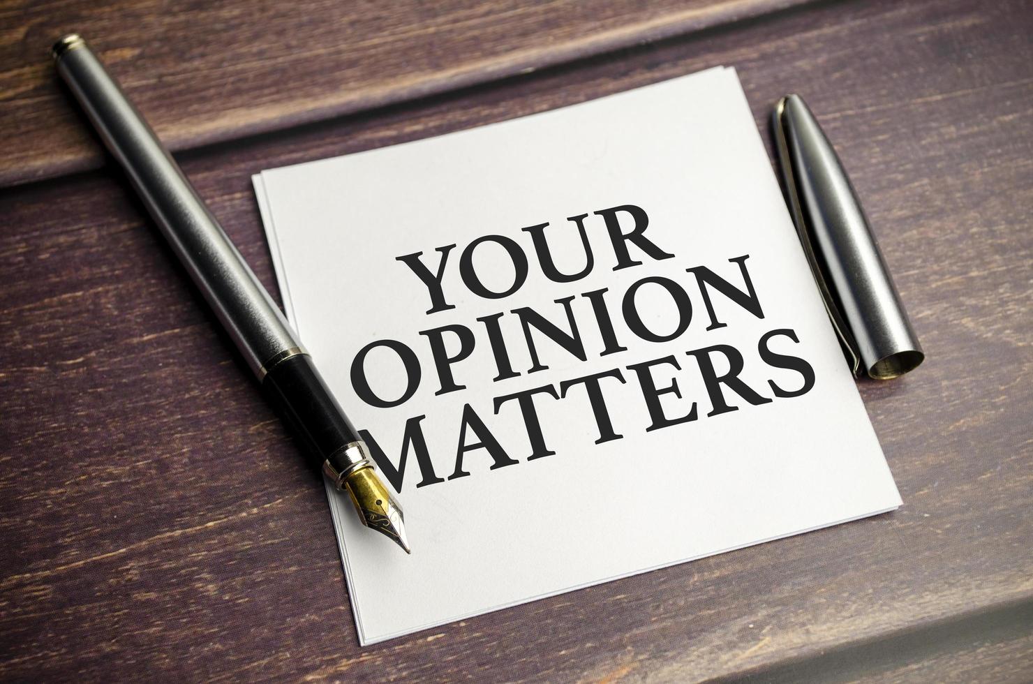 notepad with text YOUR OPINION MATTERS in the wooden background photo
