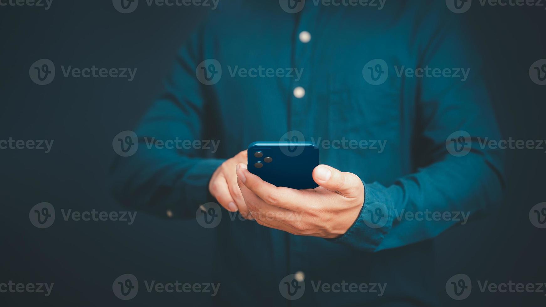 Closeup image of a man holding and using mobile phone or smartphone in room. photo