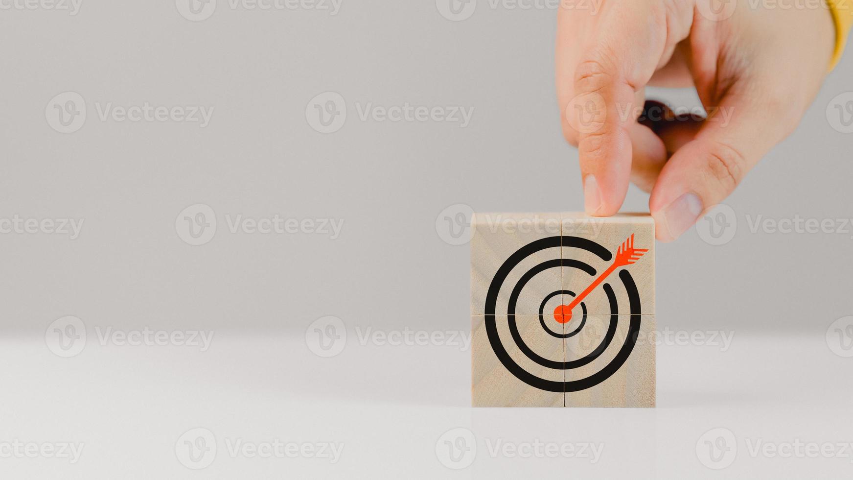 Hand put a goal icon on wooden cubes block on wood table. Business growth and goal in next year concept photo