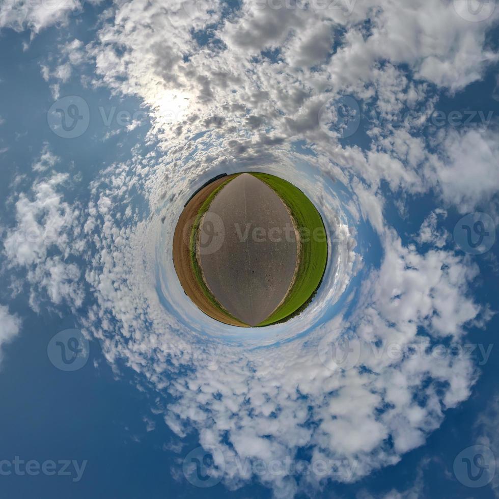 tiny planet in blue sky with beautiful clouds with transformation of spherical panorama 360 degrees. Spherical abstract aerial view. Curvature of space. photo