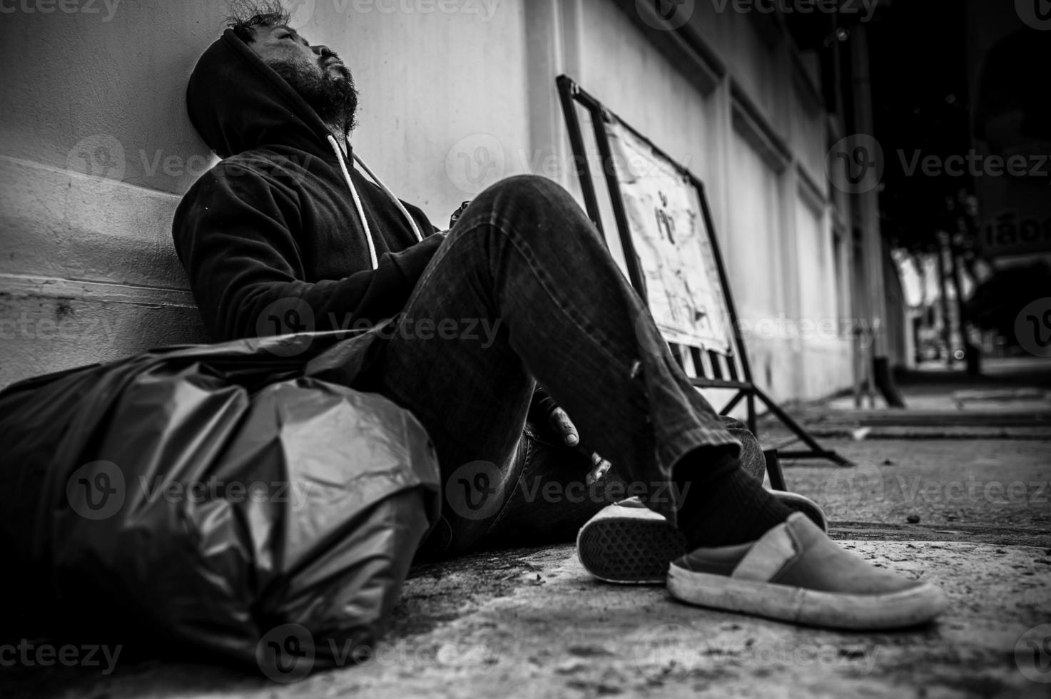 un hombre asiático no tiene hogar en la calle lateral, un extraño tiene que vivir solo en la calle porque no tiene familia. foto