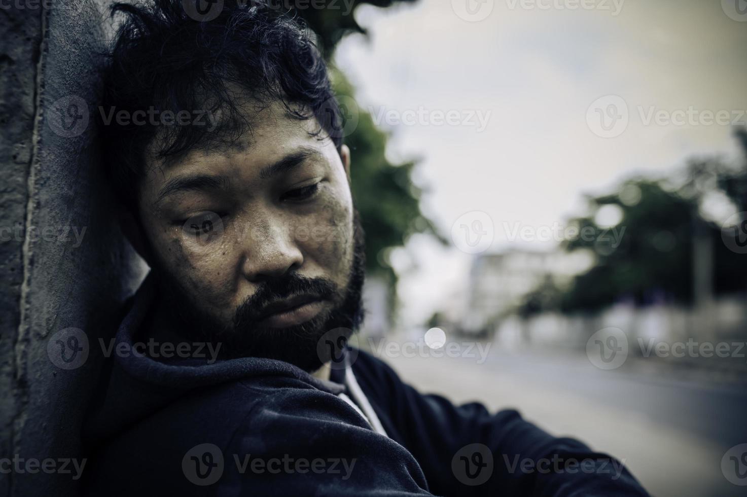 un hombre asiático no tiene hogar en la calle lateral, un extraño tiene que vivir solo en la calle porque no tiene familia. foto