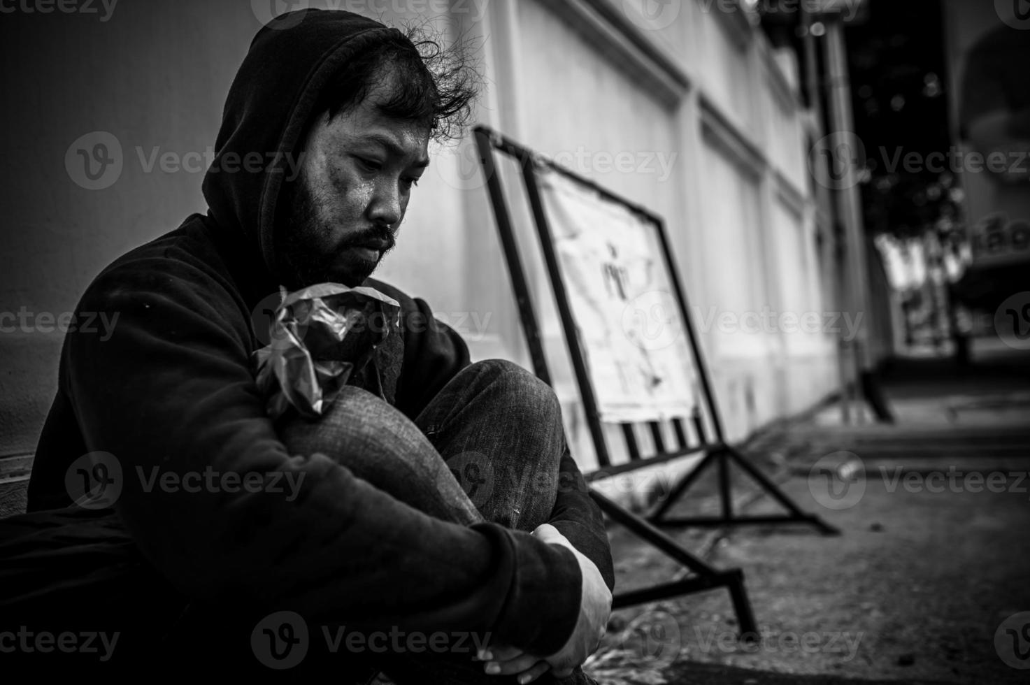 un hombre asiático no tiene hogar en la calle lateral, un extraño tiene que vivir solo en la calle porque no tiene familia. foto