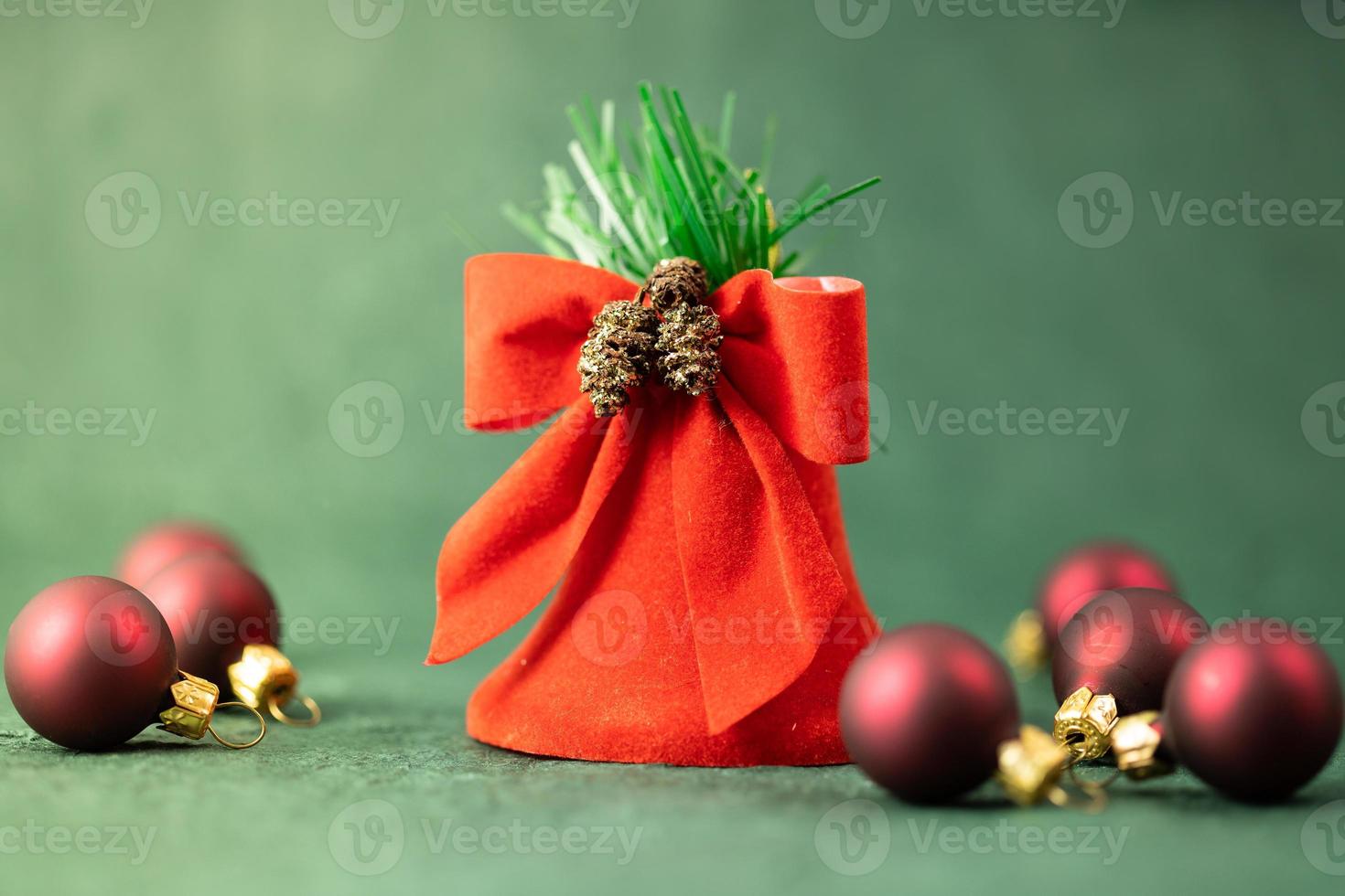 pancarta festiva, campana roja y adornos de árboles de navidad en un fondo verde foto