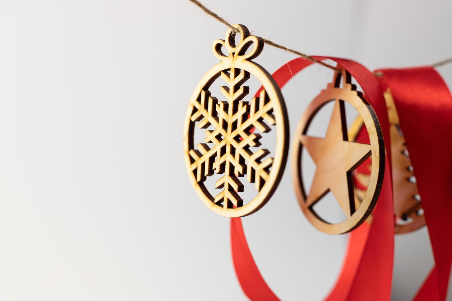 A wooden Christmas ornament hanging on a string with a red ribbon photo