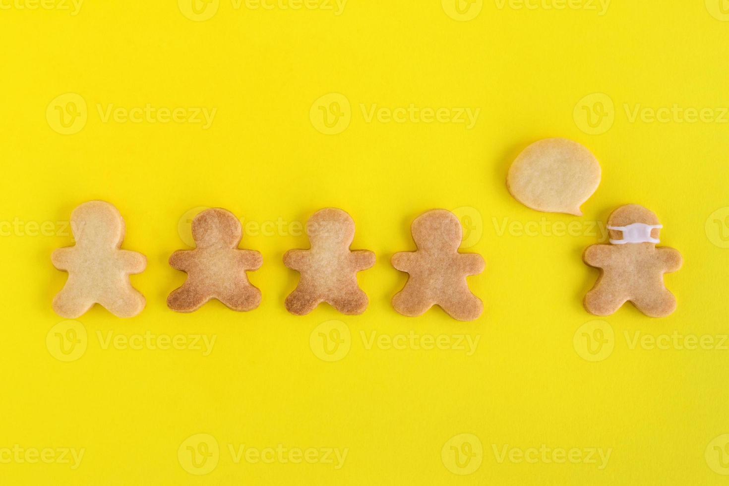 Homemade shortbread cookies with white glaze on yellow background, top view. Crowd of people and one man in face mask and with callout cloud. photo