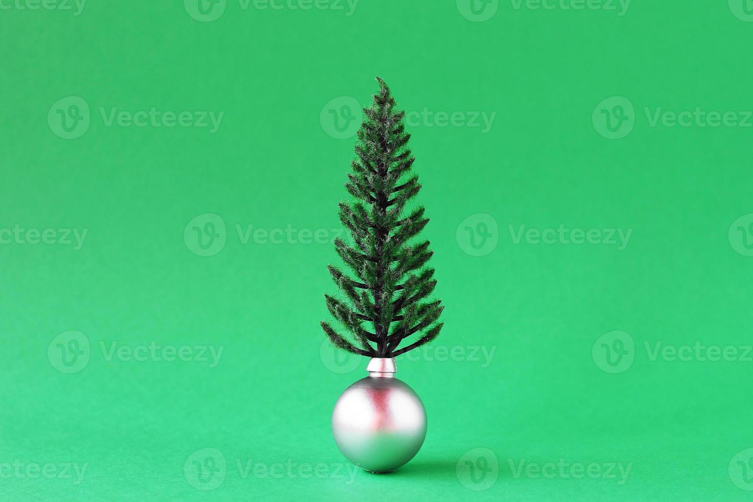 Christmas decorations - shiny silver ball artificial Christmas tree on green background with copy space. Minimal Christmas and New Year concept. photo