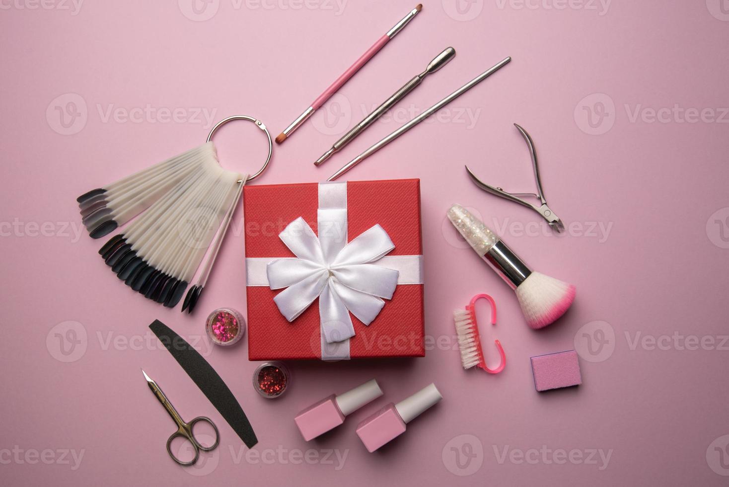 Set of manicure tools and accessories with red gift box on a pink background. Hardware manicure,Flat lay. photo