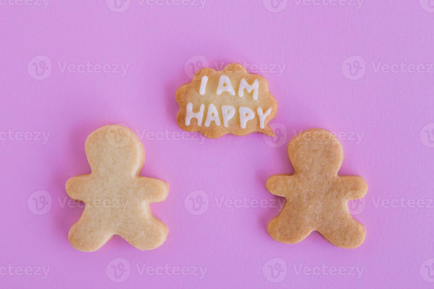 Homemade shortbread cookies with white glaze on pink background, top view. Two people with callout cloud with text - I am happy photo