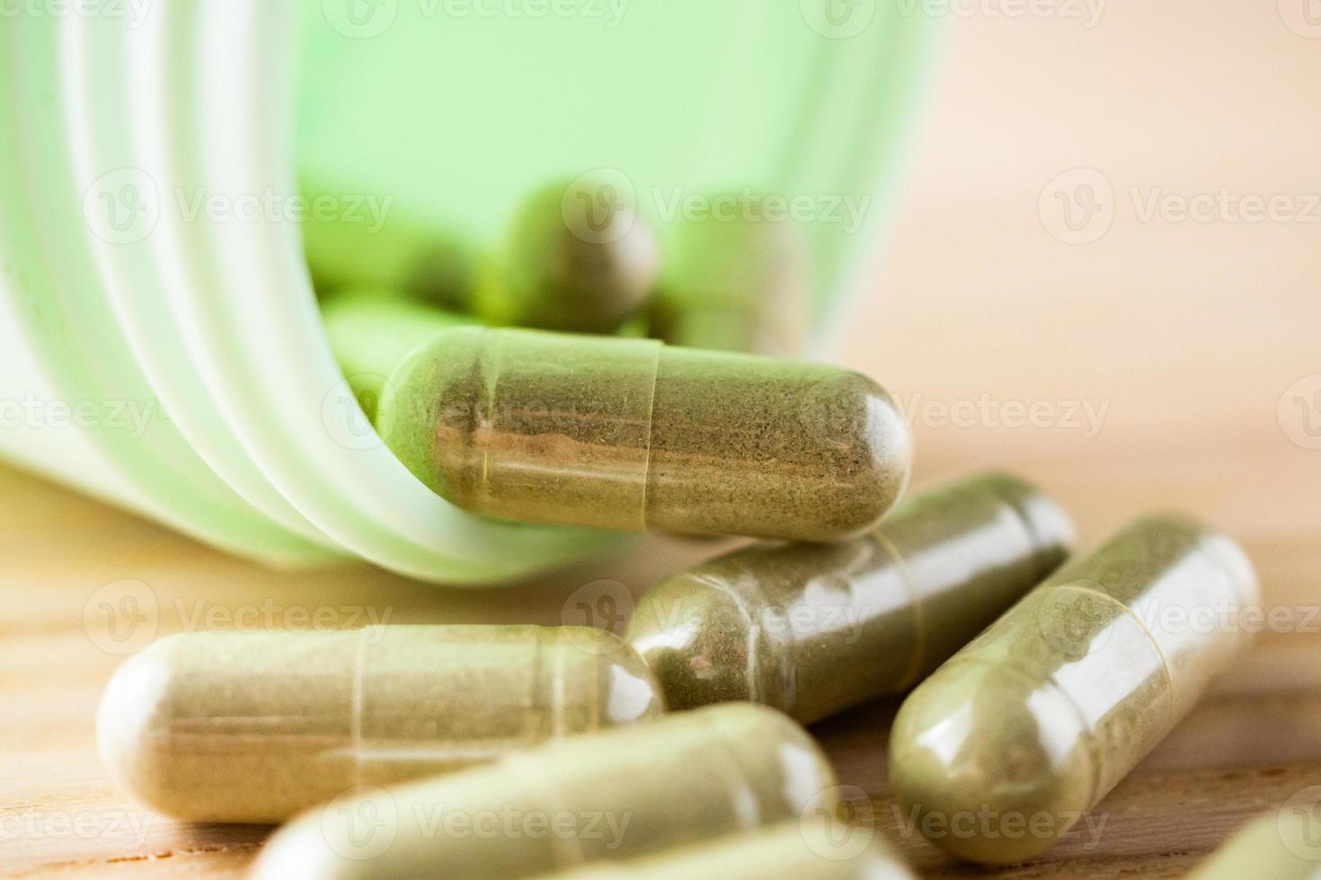 Herbal medicine capsules with bottle on wood table photo