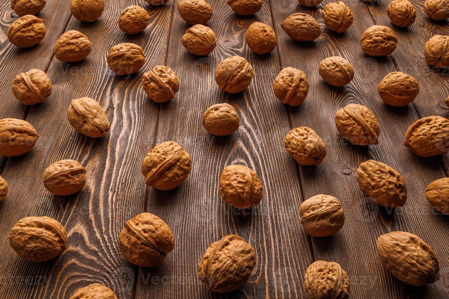 many walnuts with shells evenly spread out on brown wooden surface photo