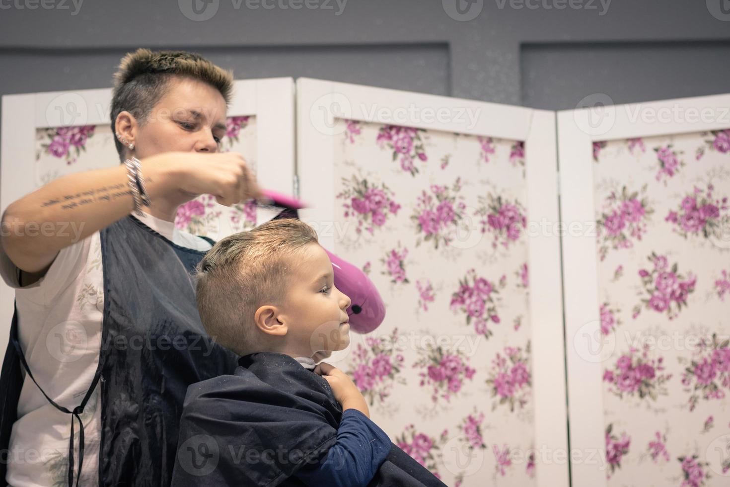 Hairdresser drying boy's hair at the salon. photo