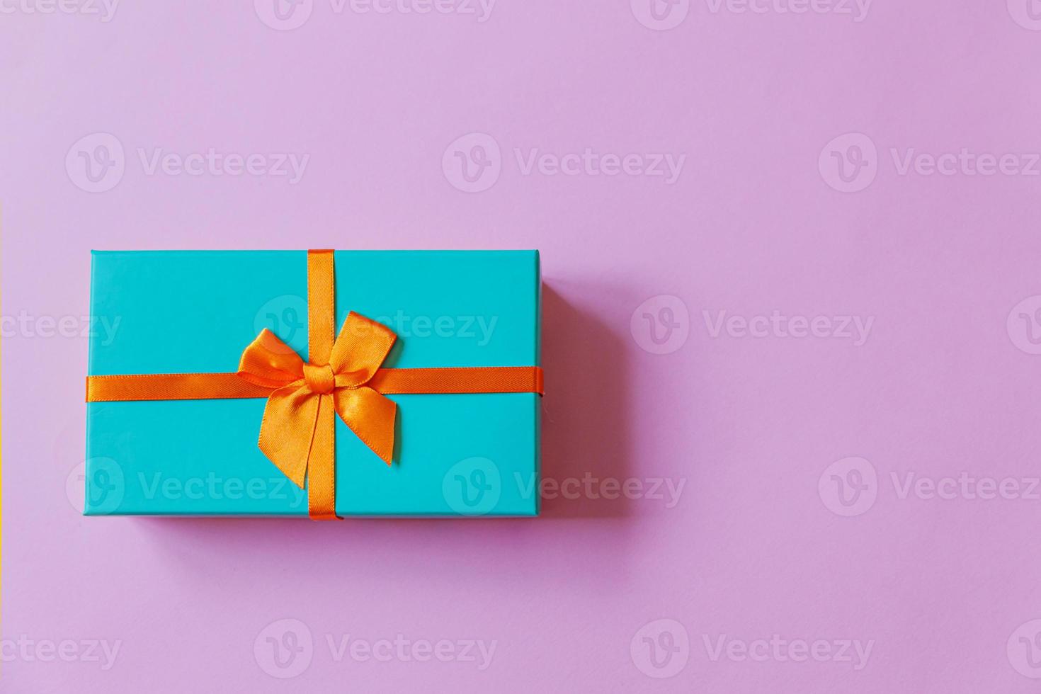 Christmas New Year birthday valentine celebration present romantic concept. Simply minimal design blue gift box isolated on violet purple colorful background. Flat lay top view, copy space photo