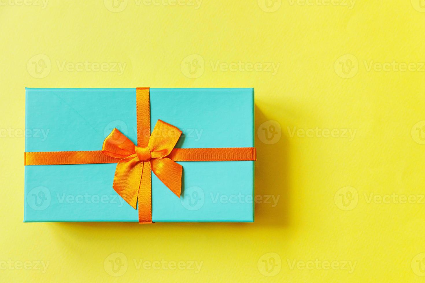 Christmas New Year birthday valentine celebration present romantic concept. Simply minimal design blue gift box isolated on yellow colorful background. Flat lay top view copy space. photo