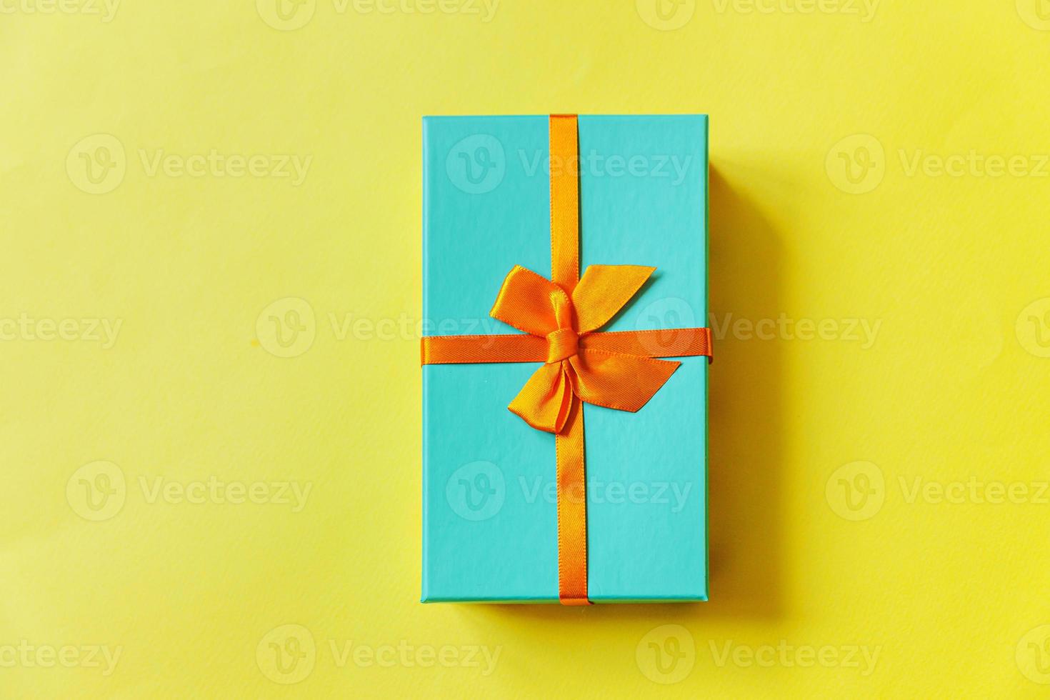 navidad año nuevo cumpleaños san valentín celebración presente concepto romántico. caja de regalo azul de diseño simplemente mínimo aislada sobre fondo amarillo colorido. espacio de copia de vista superior plana. foto