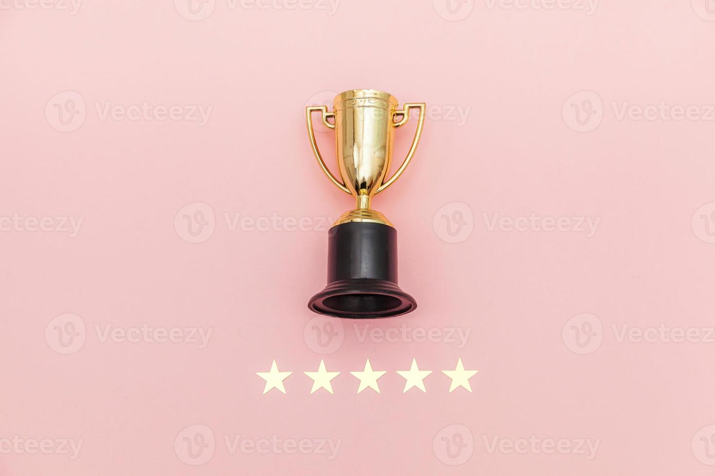 ganador de diseño simplemente plano o copa de trofeo de oro campeón y calificación de 5 estrellas aislado sobre fondo rosa pastel. victoria primer lugar de la competencia. concepto ganador o de éxito. espacio de copia de la vista superior. foto