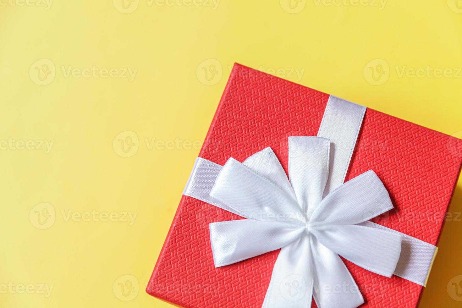 Christmas New Year birthday valentine celebration present romantic concept. Simply minimal design red gift box isolated on yellow colorful background. Flat lay top view copy space. photo