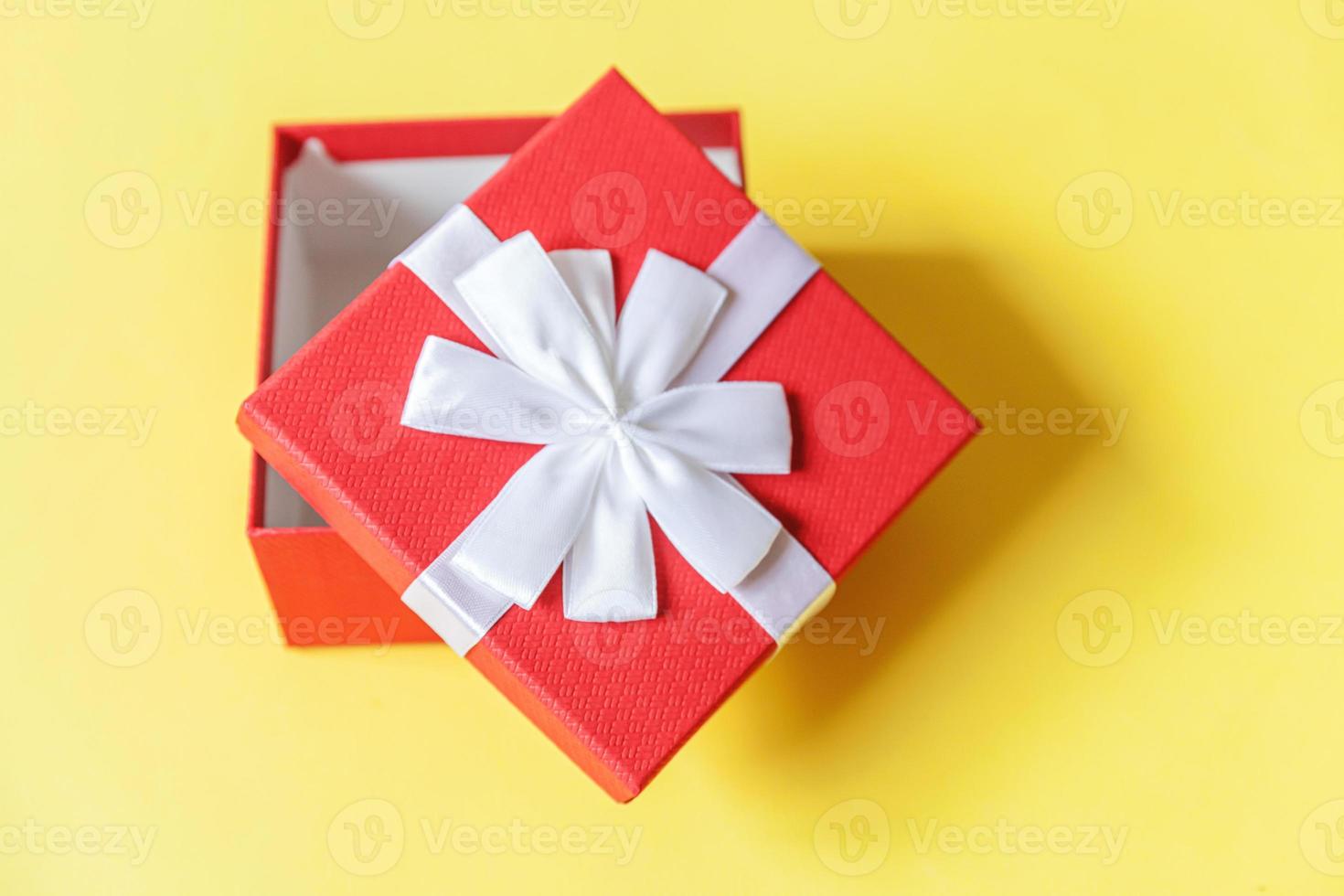 Christmas New Year birthday valentine celebration present romantic concept. Simply minimal design red gift box isolated on yellow colorful background. Flat lay top view copy space. photo