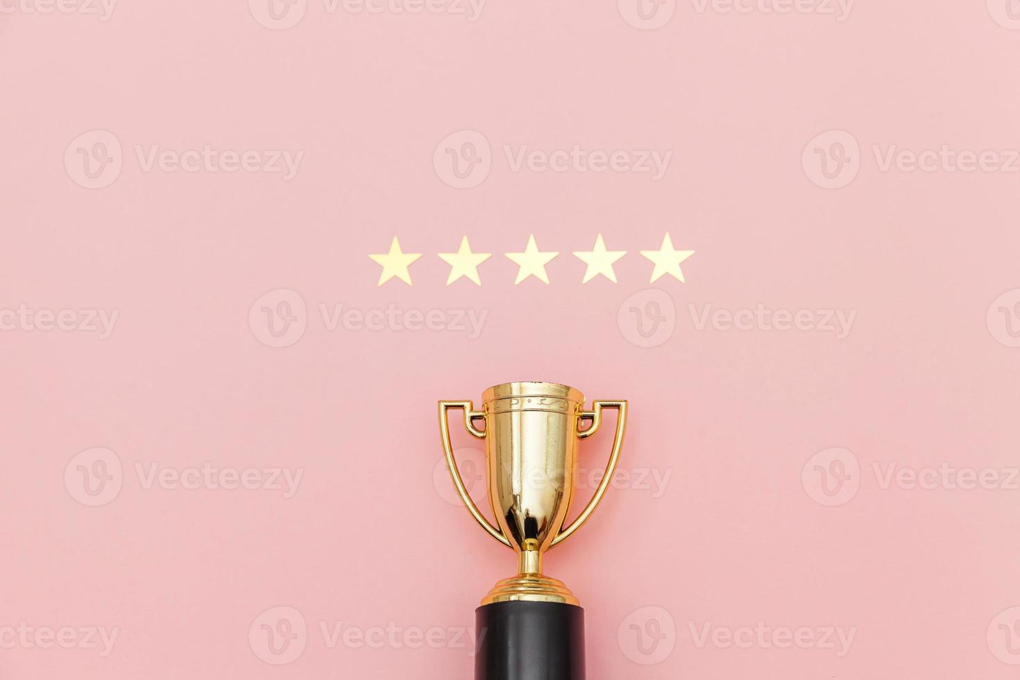 Simply flat lay design winner or champion gold trophy cup and 5 stars rating isolated on pink pastel background. Victory first place of competition. Winning or success concept. Top view copy space. photo